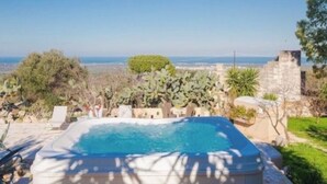 A hot tub with a clear view of the sea and a stone building in the background. - Ostuni Green Hills App. 2 - Panoramic view, charm, veranda and shared jacuzzi (Puglia)