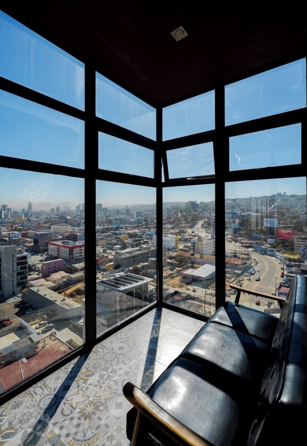 Habitación en un edificio alto con amplios ventanales y vistas a la ciudad.