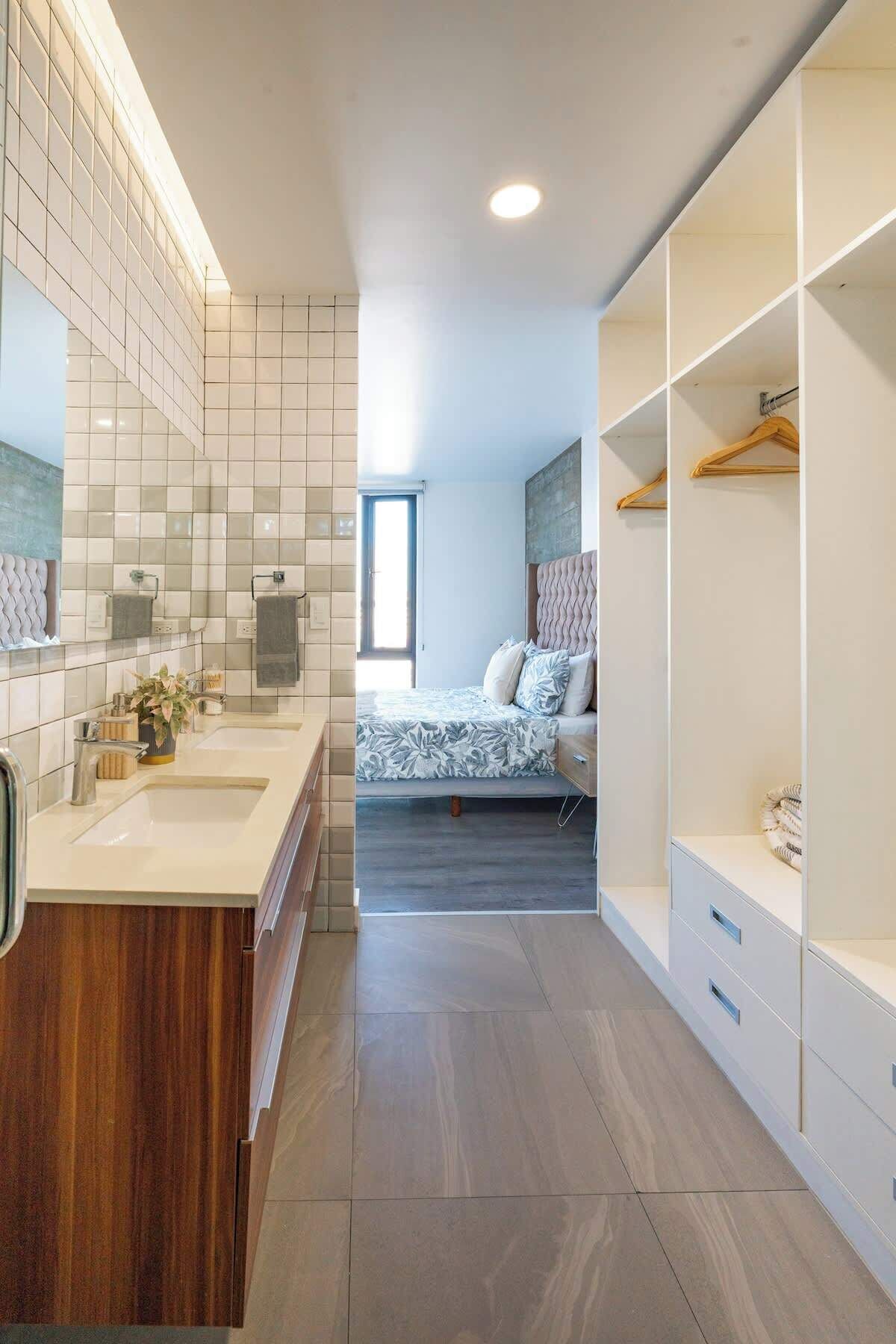 Een moderne badkamer met een wastafel, een douchegedeelte en een inloopkast met planken.