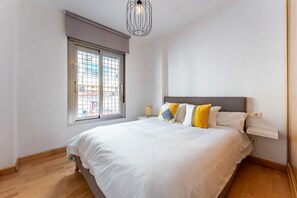 Ein Schlafzimmer mit Bett, Fenster, Nachttisch und einer Pendelleuchte.