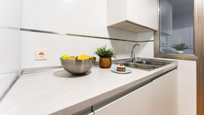 Eine Küche mit Spüle aus Edelstahl, Obstschale, kleiner Pflanze und Kuchen auf der Arbeitsfläche.