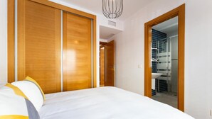 Ein Schlafzimmer mit einem Bett, einem Holzschrank und einem durch eine offene Tür einsehbaren Badezimmer.