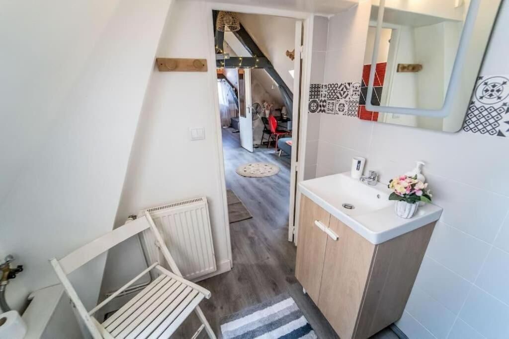 A narrow hallway leading to a bathroom with a sink and a mirror.