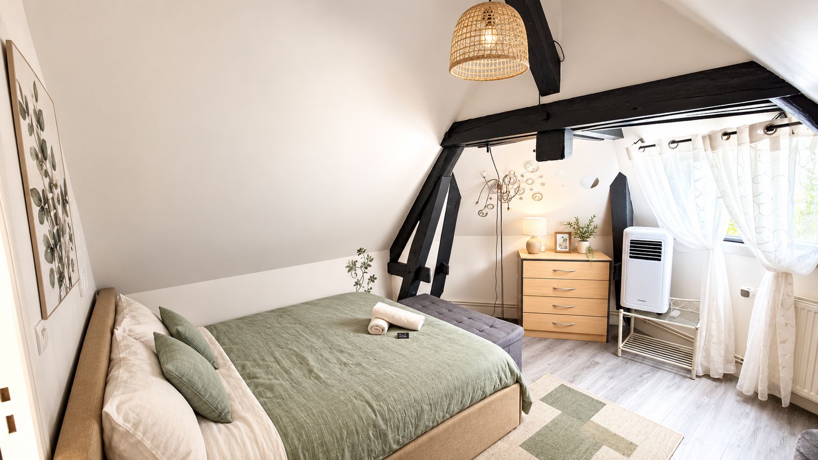 A bedroom with a bed, a desk, a radiator, and a window with curtains.