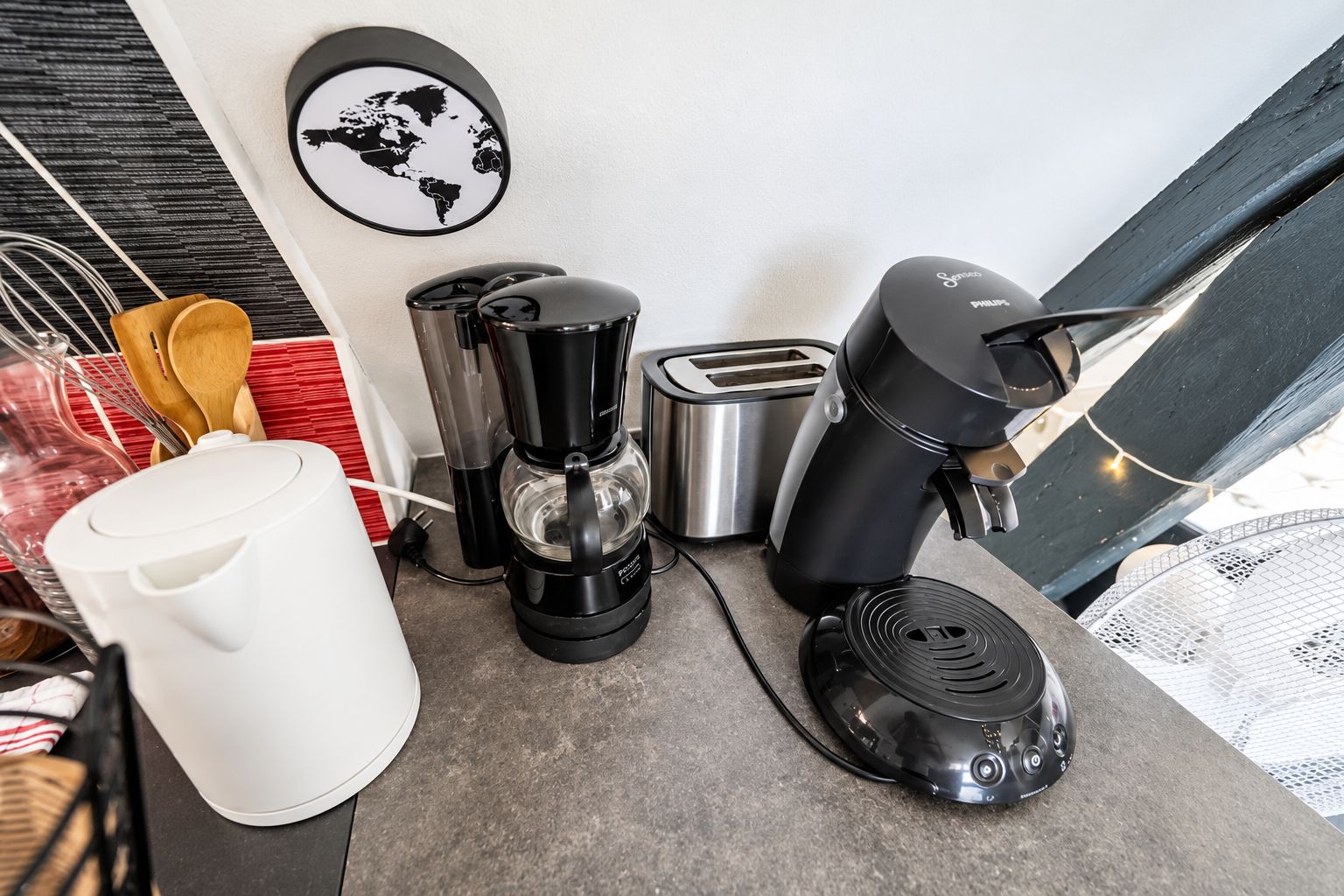 Een keuken met een koffiezetapparaat, een broodrooster en een witte waterkoker.