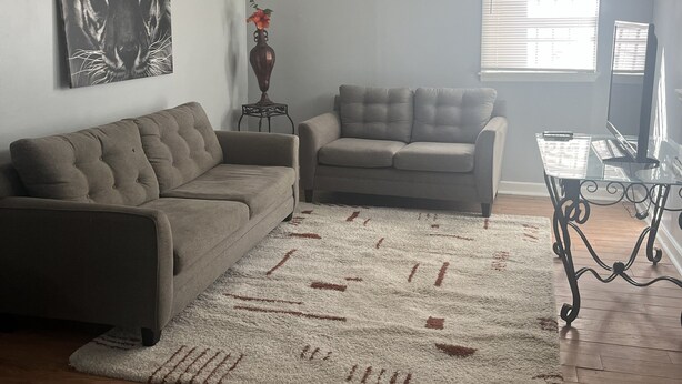 A living room with a sectional sofa, a loveseat, a decorative vase, a ceiling fan, and a window with blinds. - Serene 3-bedroom house in a pleasant Atlanta neighborhood. (Atlanta)