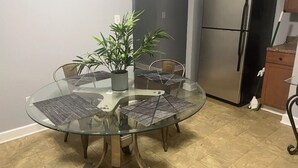 A dining area with a glass table, four chairs, a potted plant, and a stainless steel refrigerator. - Serene 3-bedroom house in a pleasant Atlanta neighborhood. (Atlanta)