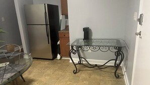 A kitchen with a stainless steel refrigerator, a glass table with metal legs, and a tiled floor. - Serene 3-bedroom house in a pleasant Atlanta neighborhood. (Atlanta)