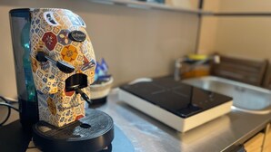 Une machine à café au design orné, posée sur un support noir.