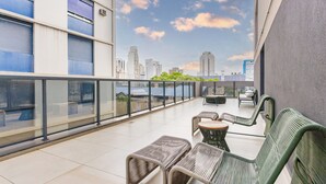 A balcony with wicker furniture, a glass railing, and a cityscape view. - Piscina Gym & Rooftop no Jardins - Luxo (São Paulo)