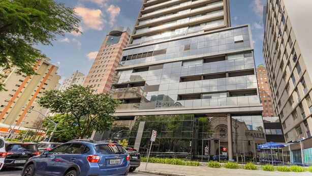 A modern building with a glass facade, multiple floors, and a parking area in front. - Piscina Gym & Rooftop no Jardins - Luxo (São Paulo)