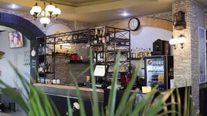 Una zona de bar con pared de piedra, un reloj y un refrigerador de Pepsi.