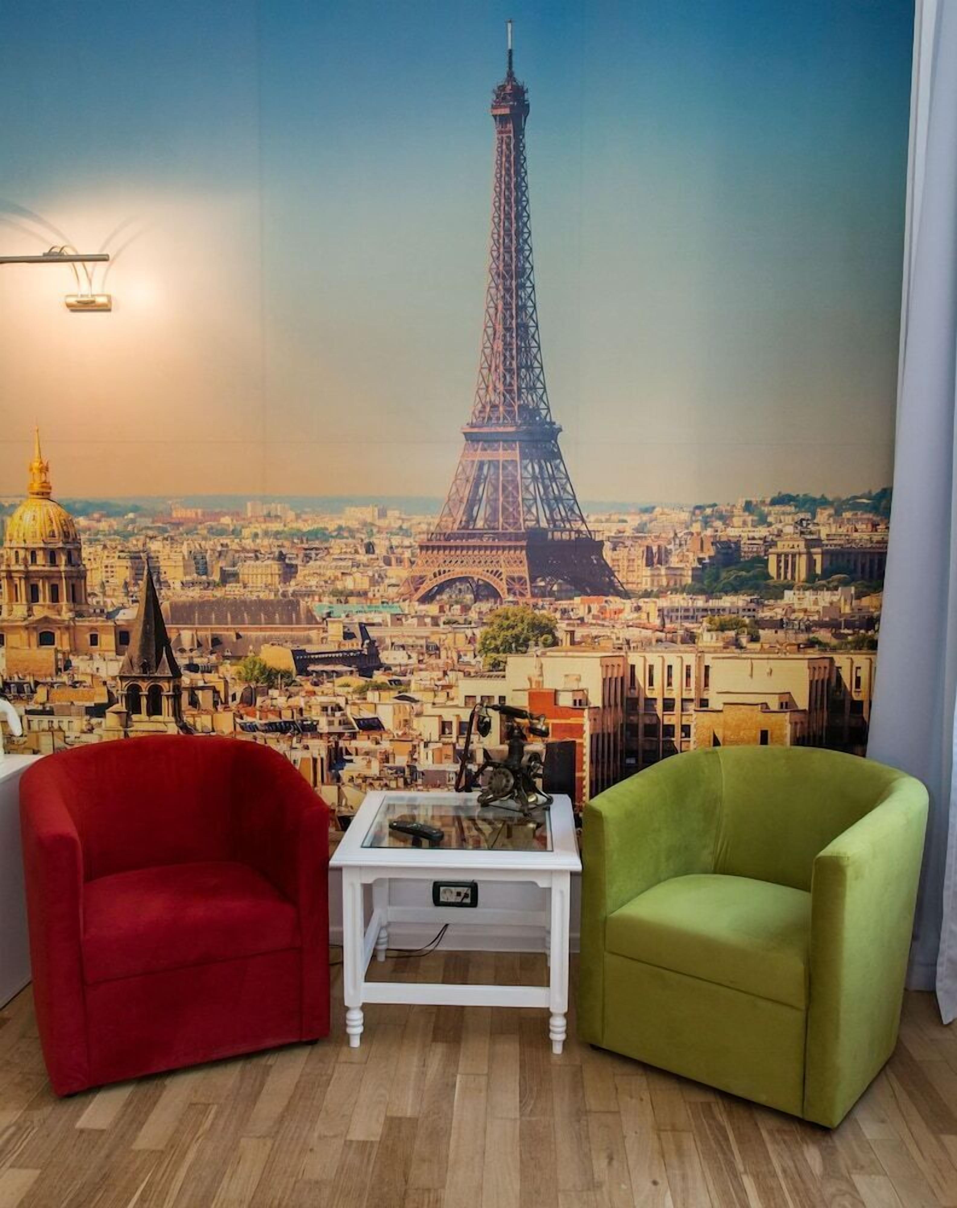 A room with a mural of the Eiffel Tower, two chairs, and a small table.