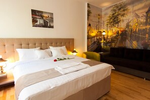 Una habitación de hotel con una cama grande, una mesita de noche, una lámpara, un sillón verde y un mural de un paisaje urbano.