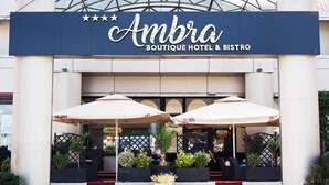 Exterior del Ambra Boutique Hotel & Bistro, con letrero, zona de estar al aire libre y escalones que conducen a la entrada.