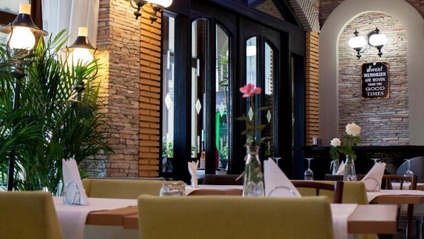 Interior de restaurante con paredes de ladrillo, vigas de madera y un letrero que dice 'Sweet Memories Are Woven from the Good Times'.