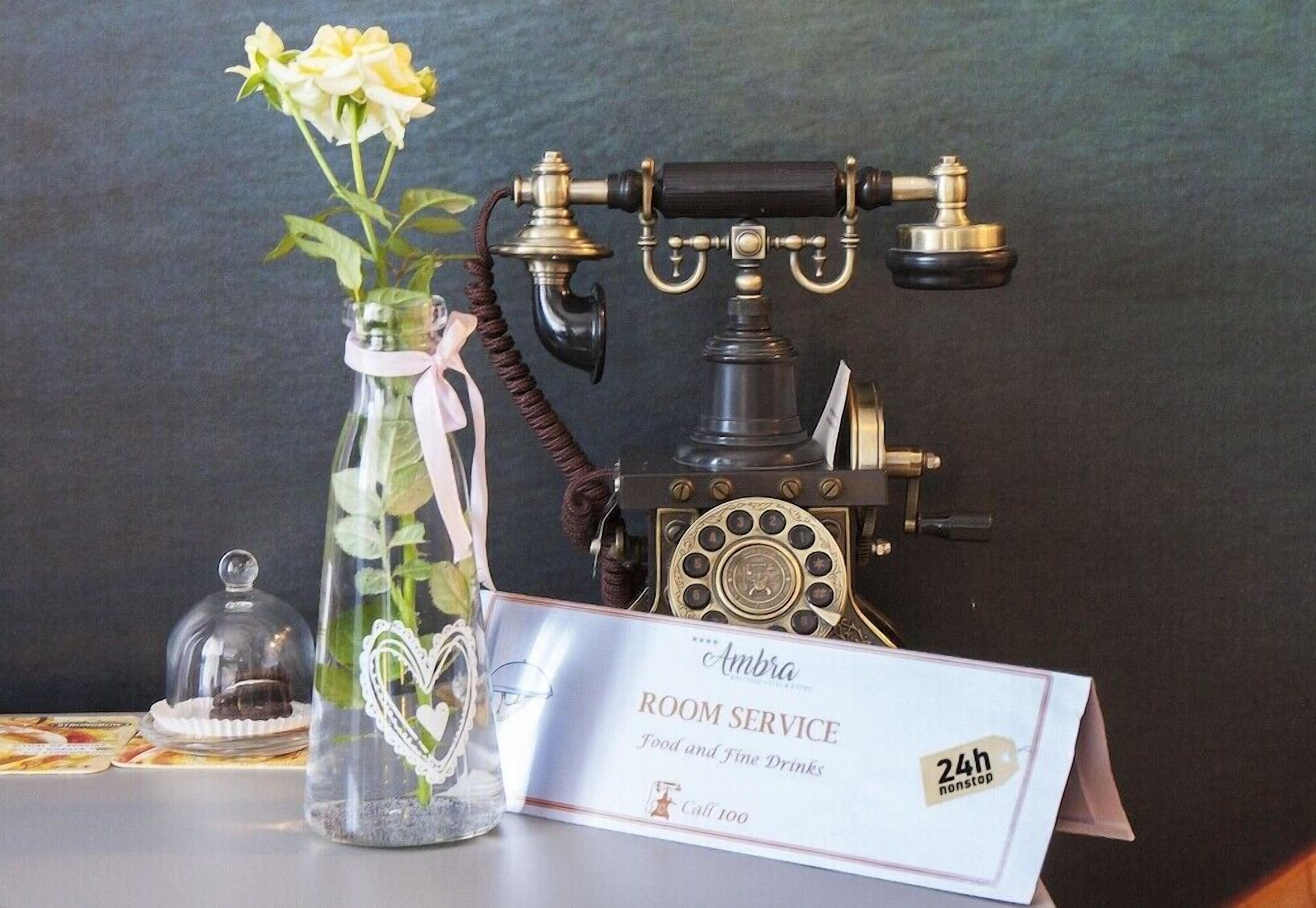 A vintage telephone, a glass vase with a heart design, and a room service sign.