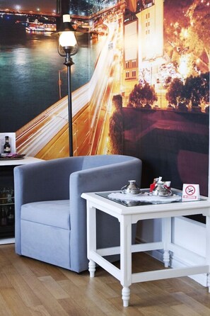 A room with a view of a cityscape at night, a modern chair, a small table with a teapot, and a 'no smoking' sign. - Ambra Boutique Hotel And Bistro (Constanta)