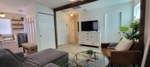 A living room with a sofa, a glass coffee table, a TV, and a cabinet. - Private Bungalow in Downtown Las Vegas (Las Vegas)