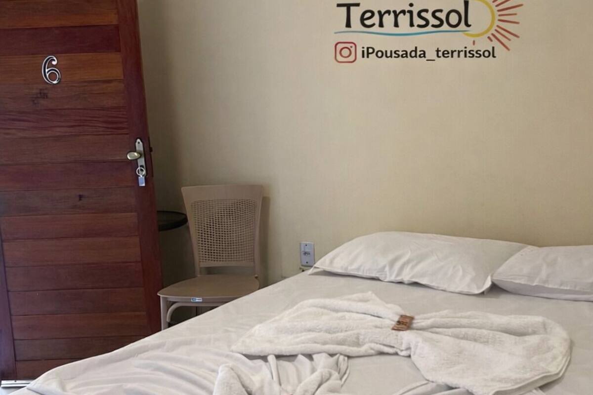 Habitación de hotel con cama, toallas blancas, puerta de madera y una pared con el logotipo y el nombre de usuario de Instagram del hotel.