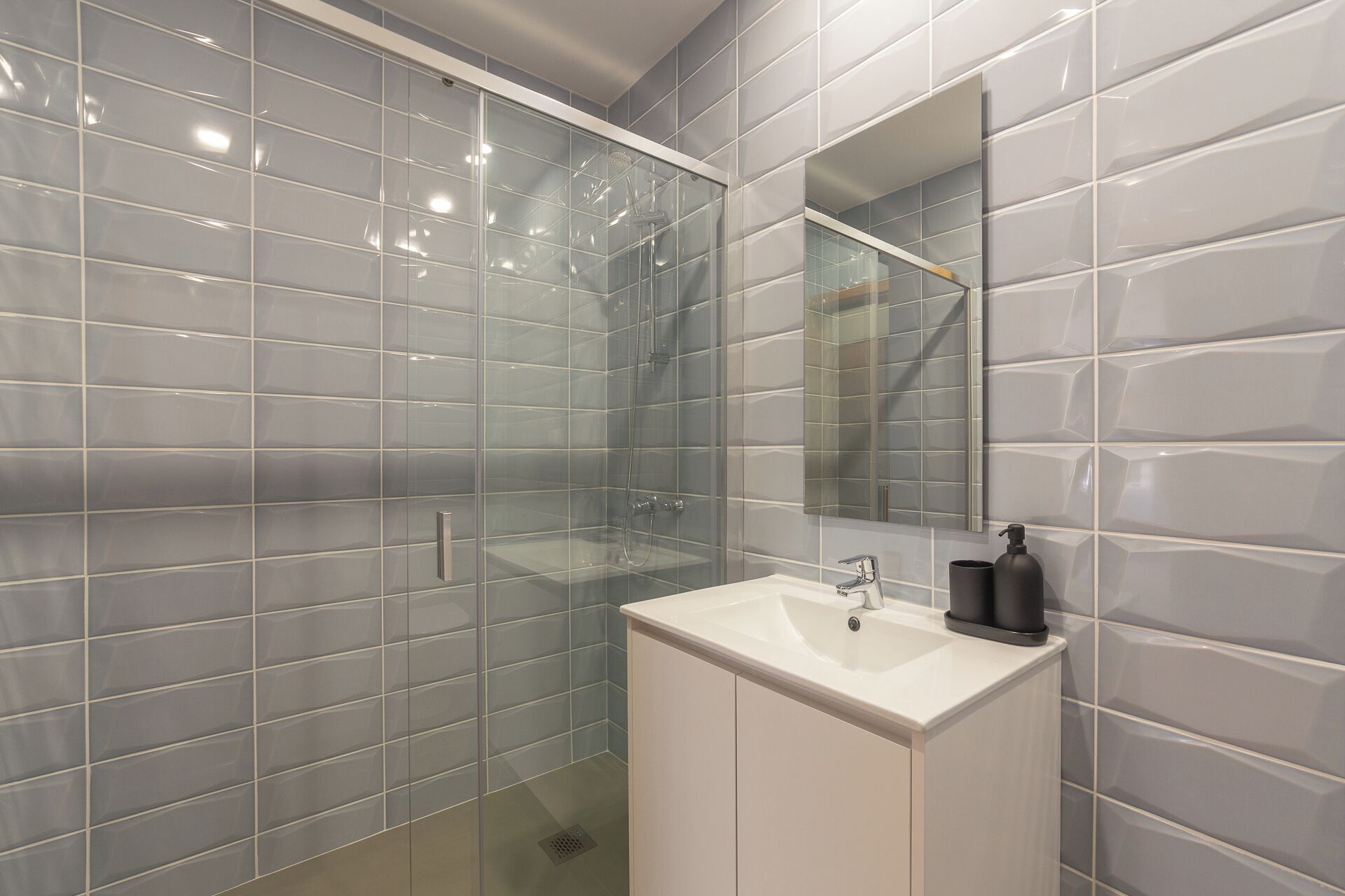 Une salle de bain avec une douche à parois de verre, un lavabo blanc et un miroir.