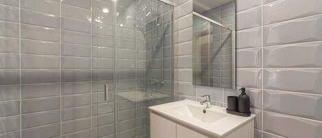 Une salle de bain avec une douche à parois de verre, un lavabo blanc et un miroir.