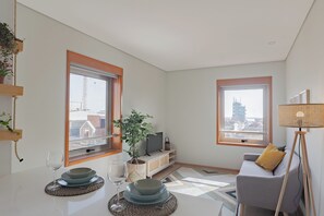 Uma sala de estar moderna com sofá, televisão e área de jantar com pratos e copos.