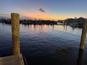 A waterfront dock with wooden posts, calm water, and distant buildings.