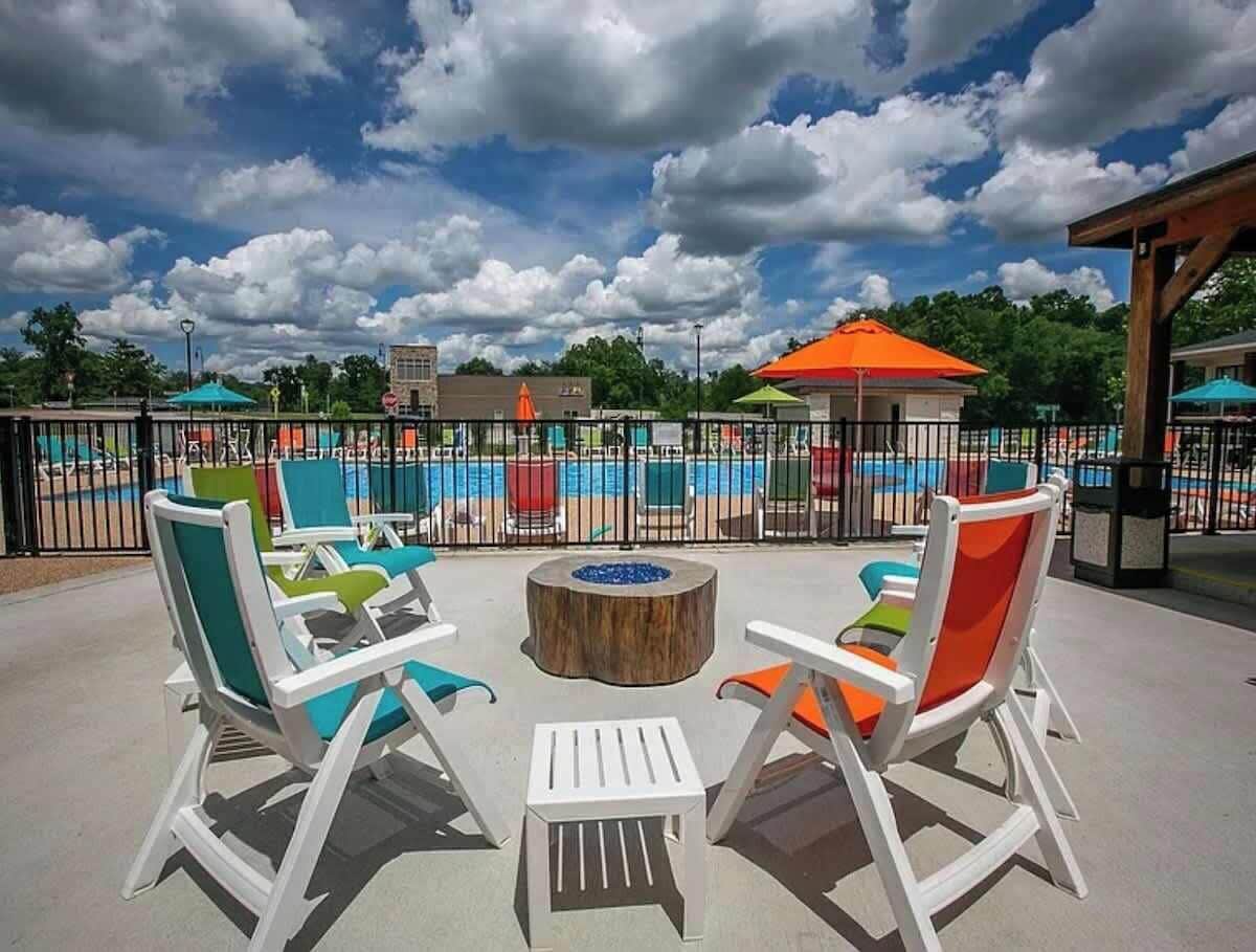 Espace extérieur aménagé avec un foyer, une piscine et une zone couverte dotée d’un toit orange.