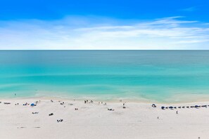 A beach with people and umbrellas, a clear sky, and calm water. - Majestic Sun A1105 • Big Views • Pools & Hot Tubs • Beach Gear • Gym • Tennis (Miramar Beach)