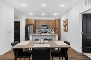 Une cuisine moderne avec des meubles en bois, un îlot central et un coin repas comprenant une table et des chaises.