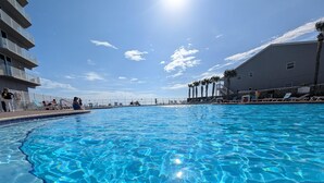 A clear blue swimming pool with a view of the sky and palm trees. - Luxe Tidewater Penthouse sleeps 10 (Panama City Beach)