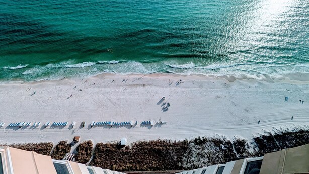 A beach with rows of sun loungers and a staircase leading down to the shore. - Luxe Tidewater Penthouse sleeps 10 (Panama City Beach)