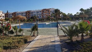 Ein Resort mit Schwimmbad, Palmen und einem Gebäude mit mehreren Balkonen.