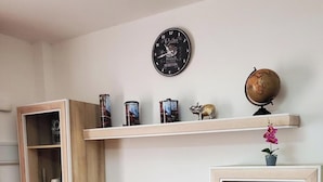 Ein Wohnzimmer mit Fernseher, Holzregalen, einem Globus und Dekorationselementen.