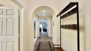 Un pasillo con una puerta blanca, un arco y un perchero.