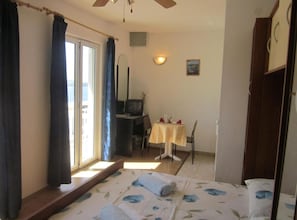 A bedroom with a bed, a desk, a chair, a television, and a small table with a tablecloth. - Azure Hvar Residence (Hvar)