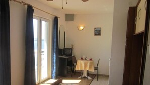A bedroom with a bed, a desk, a chair, a television, and a small table with a tablecloth. - Azure Hvar Residence (Hvar)