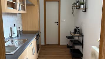 Eine Küche mit Holzausstattung, einer schwarzen Arbeitsplatte, einer Spüle aus Edelstahl und einem Deckenventilator.
