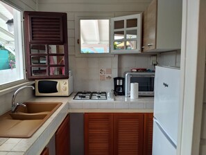 Eine kleine Küche mit Spüle, Herd, Mikrowelle und Kühlschrank.