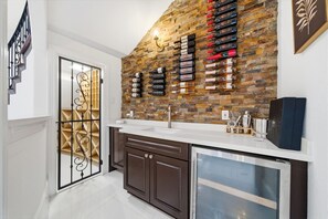 A modern kitchen with a brick backsplash, wine rack, and a built-in refrigerator. - Heights Retreat | Heated Pool/Spa | Elevator (Houston)