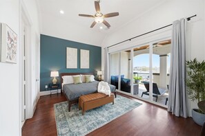 Una camera da letto con un letto, comodini, una ventola a soffitto e vista su un balcone.