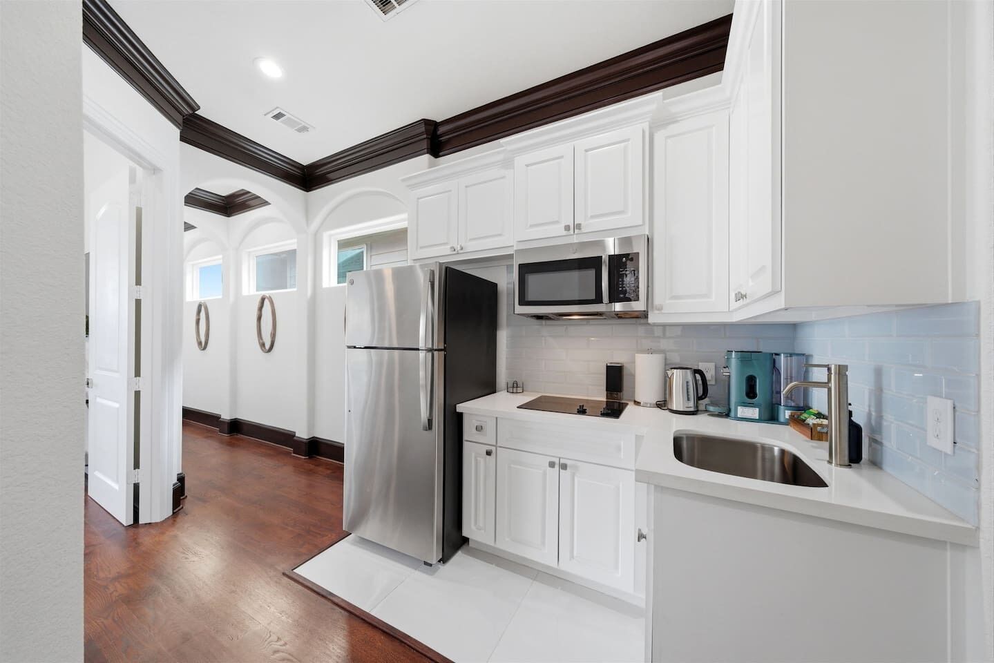 Una cocina moderna con armarios blancos, electrodomésticos de acero inoxidable y salpicadero de azulejos azules.