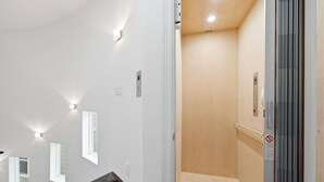 Een gang met een houten vloer, witte muren en inbouwverlichting.