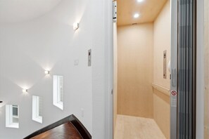 A hallway with a wooden floor, white walls, and recessed lighting. - Heights Retreat | Heated Pool/Spa | Elevator (Houston)