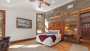 Ein Schlafzimmer mit einem Bett, einem Deckenventilator, einem Gemälde und einer Holzwand.