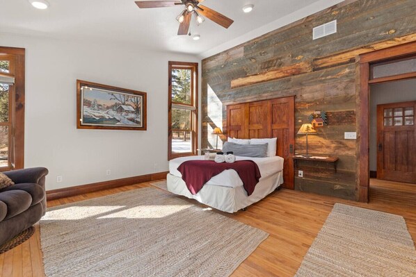 Une chambre à coucher avec un lit, un ventilateur de plafond, un tableau et un mur en bois.