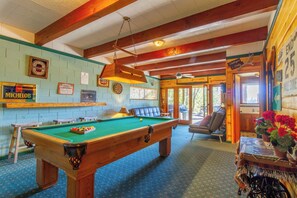 Een pooltafel in een ruimte met houten balken, een dartbord en een biljarttafel.