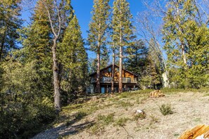 A cabin surrounded by tall pine trees, with a clear sky above. - Lakefront Chalet in Bass Lake Cove with private dock (Bass Lake)