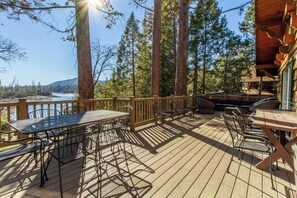 Une terrasse en bois, agréée de mobilier d’extérieur, qui offre une vue sur un lac et une forêt.